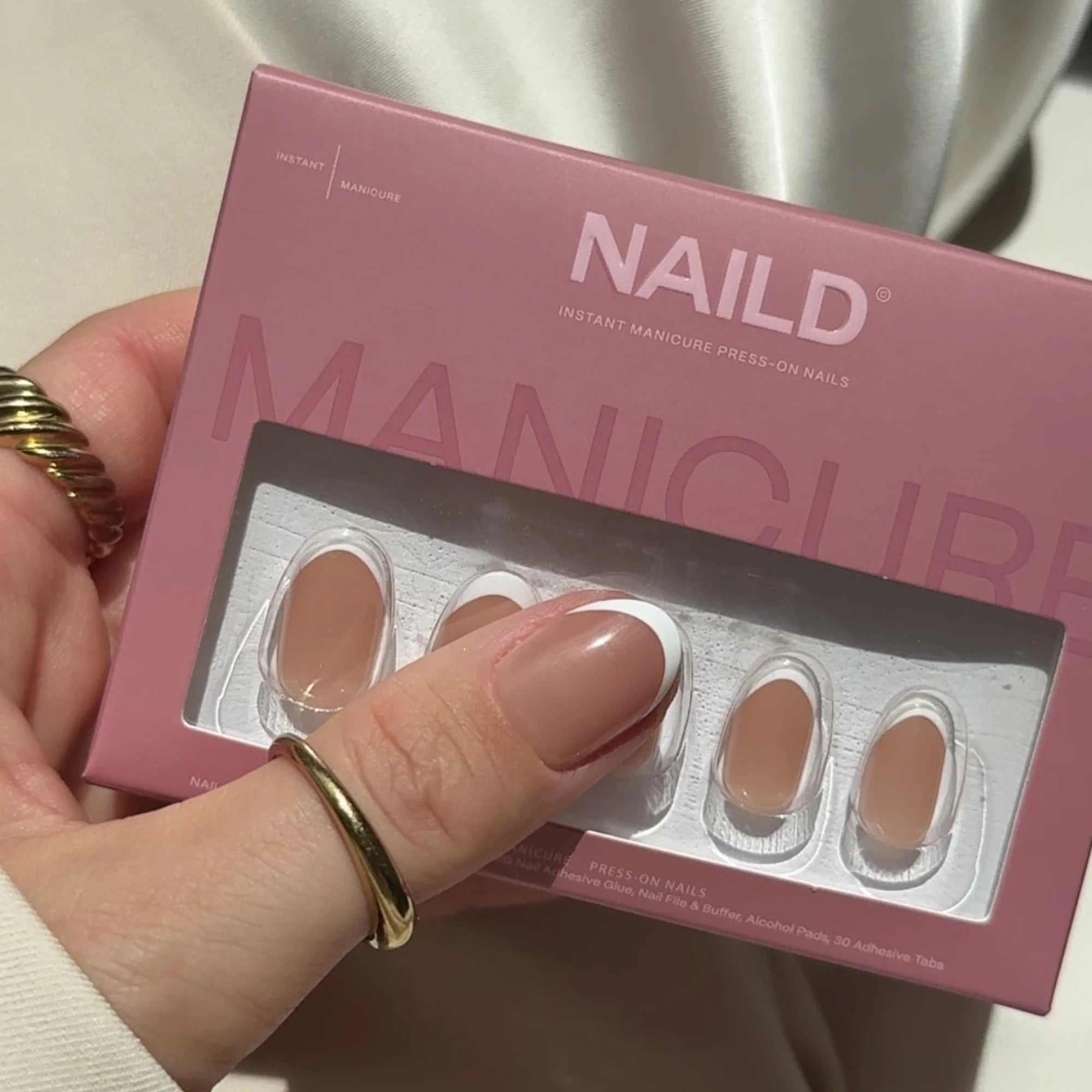 NAILD French Round Infilled Press-On Nails Verpackung in der Hand – Lifestyle