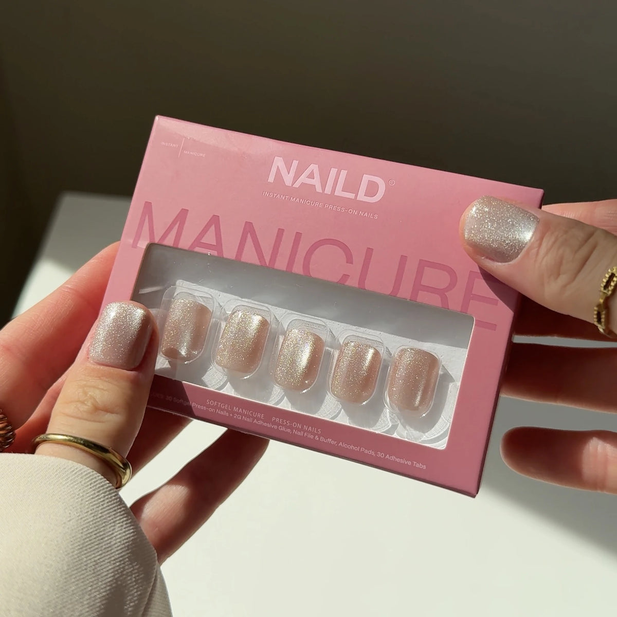NAILD Pixie Blush XXS Square Press-On Nails Verpackung in der Hand – Lifestyle